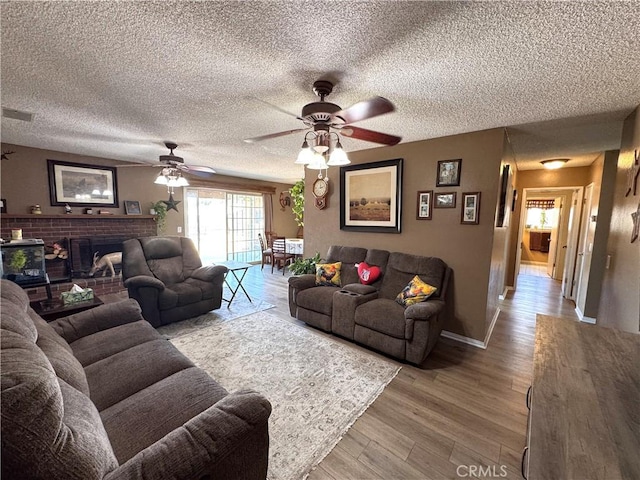 811 Mescal Dr, Barstow, CA 92311 - living area with a ceiling fan, a fireplace, a textured ceiling, and wood finished floors