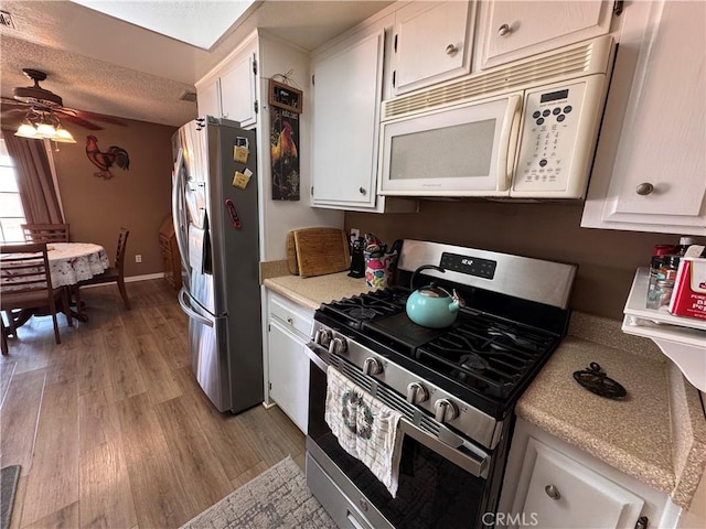 811 Mescal Dr, Barstow, CA 92311 - kitchen featuring stainless steel appliances, light wood-style floors, white cabinetry, light countertops, and a ceiling fan