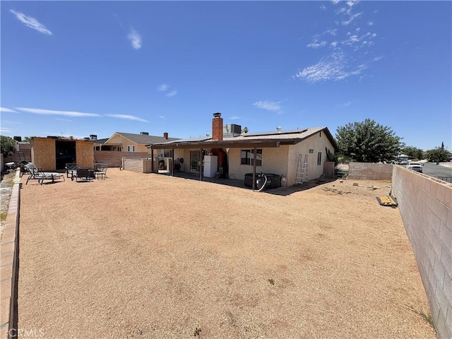 811 Mescal Dr, Barstow, CA 92311 - back of property with roof mounted solar panels, a fenced backyard, a patio, and a chimney