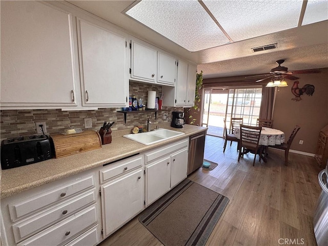 811 Mescal Dr, Barstow, CA 92311 - kitchen with stainless steel dishwasher, white cabinetry, decorative backsplash, a ceiling fan, and a textured ceiling