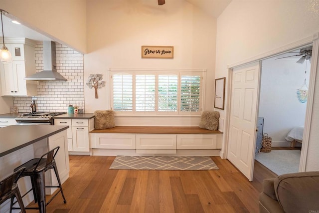 39668 Roripaugh Rd, Temecula, CA 92591 - kitchen featuring wall chimney exhaust hood, ceiling fan, white cabinets, light wood-style flooring, and high vaulted ceiling