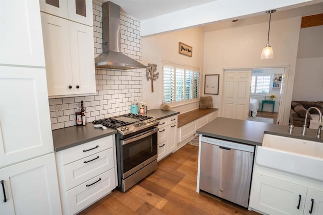 39668 Roripaugh Rd, Temecula, CA 92591 - kitchen featuring appliances with stainless steel finishes, wall chimney exhaust hood, dark countertops, decorative backsplash, and white cabinetry