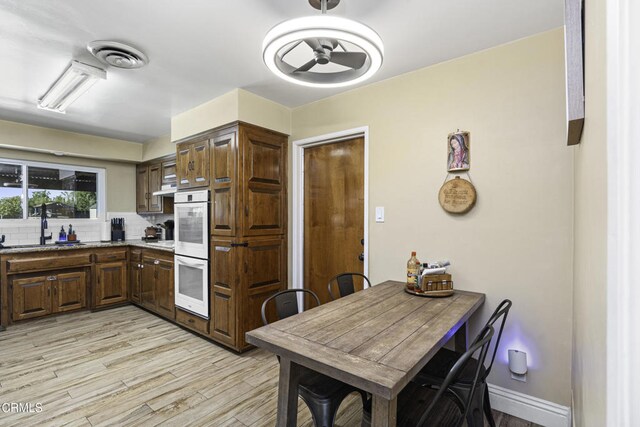 6100 Carter Ave, Bakersfield, CA 93308 - kitchen with double oven, light wood-style flooring, backsplash, and a ceiling fan