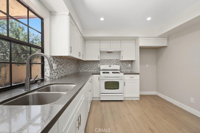 2639 Cameron Unit 119, Anaheim, CA 92801 - kitchen featuring white range with gas stovetop, light wood finished floors, backsplash, white cabinetry, and recessed lighting