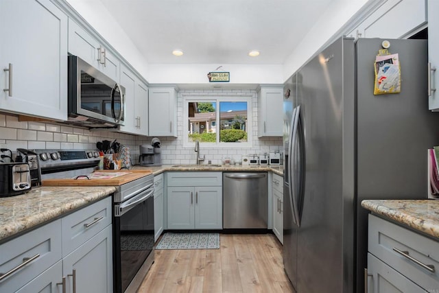 4396 Albatross Way, Oceanside, CA 92057 - kitchen featuring appliances with stainless steel finishes, light wood finished floors, backsplash, light stone counters, and recessed lighting