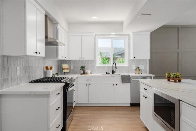 413 N Rimhurst Ave, Covina, CA 91724 - kitchen featuring appliances with stainless steel finishes, wall chimney range hood, light stone countertops, tasteful backsplash, and white cabinets
