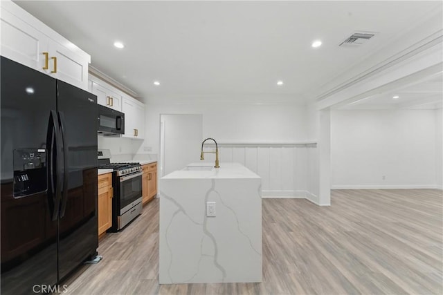 5171 S Wilton Pl, Los Angeles, CA 90062 - kitchen featuring black appliances, light stone countertops, light wood-style floors, open floor plan, and wainscoting