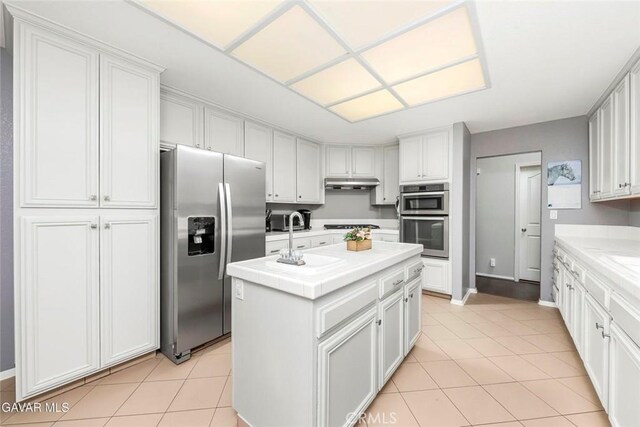 4018 Via Barbara, Lancaster, CA 93536 - kitchen with appliances with stainless steel finishes, an island with sink, light tile patterned flooring, and under cabinet range hood