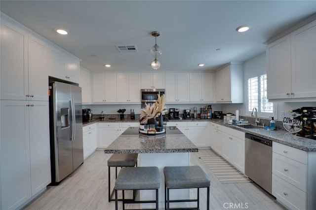 15147 Ridge Ln Unit 5, Fontana, CA 92336 - kitchen with appliances with stainless steel finishes, a center island, white cabinets, light wood-type flooring, and a breakfast bar area