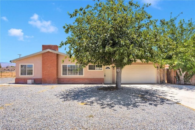 21815 Jelan Ave, Apple Valley, CA 92307 - view of front of house featuring an attached garage, gravel driveway, a chimney, brick siding, and stucco siding