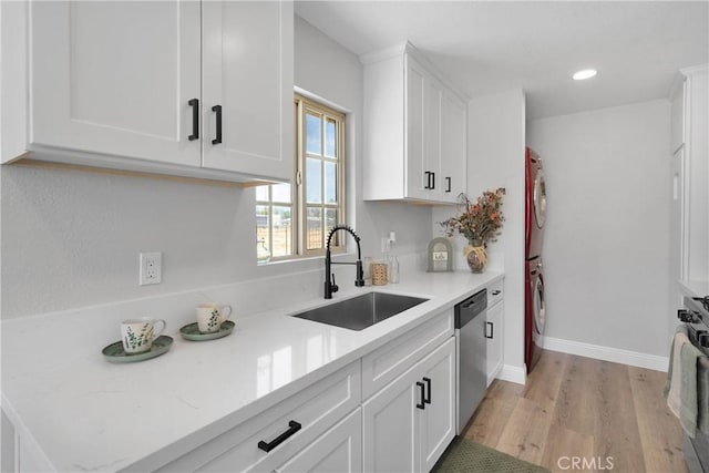 21815 Jelan Ave, Apple Valley, CA 92307 - kitchen with stacked washer / dryer, white cabinetry, light countertops, stainless steel dishwasher, and light wood-style flooring