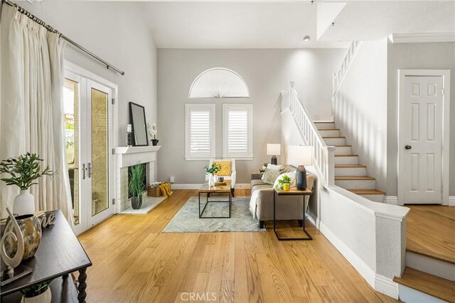 24343 Landover Rd Unit 139, Laguna Hills, CA 92653 - living room with stairway, light wood-style flooring, a high ceiling, and a fireplace with raised hearth
