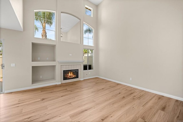 4625 Los Alamos Way Unit C, Oceanside, CA 92057 - unfurnished living room featuring a high ceiling, wood finished floors, built in shelves, and a tiled fireplace