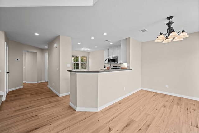 4625 Los Alamos Way Unit C, Oceanside, CA 92057 - kitchen with stainless steel microwave, light wood-style flooring, a chandelier, recessed lighting, and white cabinetry