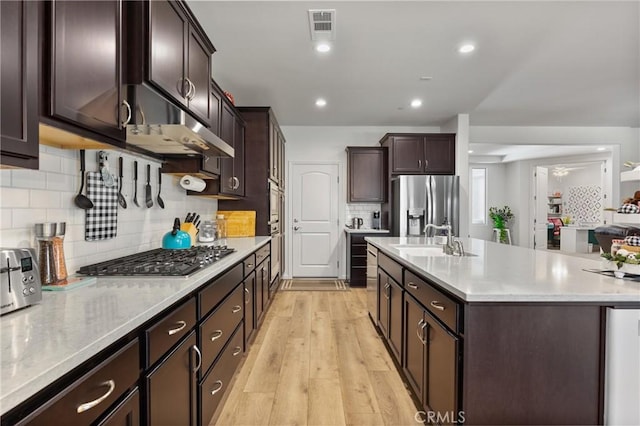 14217 Pemberley Passage Ave, Bakersfield, CA 93311 - kitchen featuring appliances with stainless steel finishes, under cabinet range hood, a kitchen island with sink, dark brown cabinetry, and recessed lighting