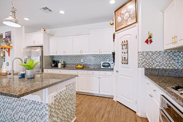 26947 Mountaingate St, Menifee, CA 92585 - kitchen with stainless steel appliances, white cabinetry, backsplash, light wood-style flooring, and decorative light fixtures