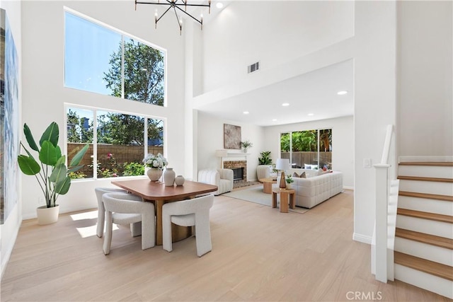 15 Lyon Rdg, Aliso Viejo, CA 92656 - dining space featuring a high ceiling, stairs, a fireplace with raised hearth, light wood-type flooring, and a chandelier