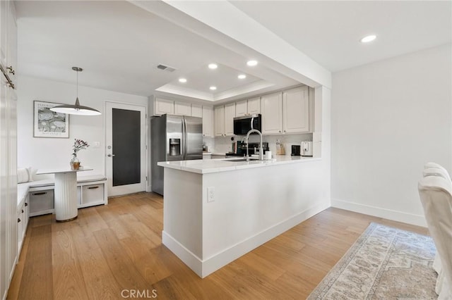 8396 Goldsport Cir, Huntington Beach, CA 92646 - kitchen with appliances with stainless steel finishes, light wood finished floors, a peninsula, recessed lighting, and a raised ceiling