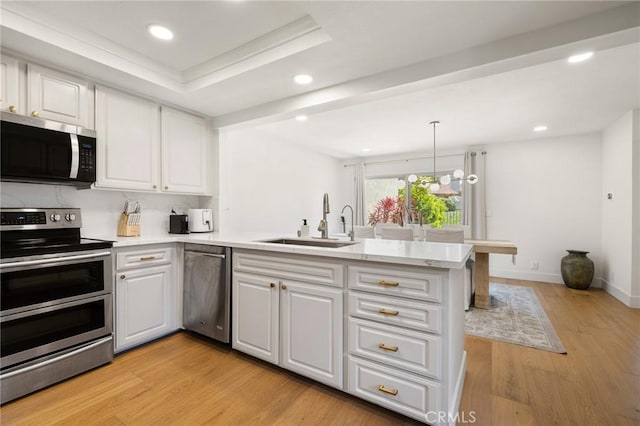 8396 Goldsport Cir, Huntington Beach, CA 92646 - kitchen featuring appliances with stainless steel finishes, a peninsula, light wood-style flooring, white cabinetry, and recessed lighting