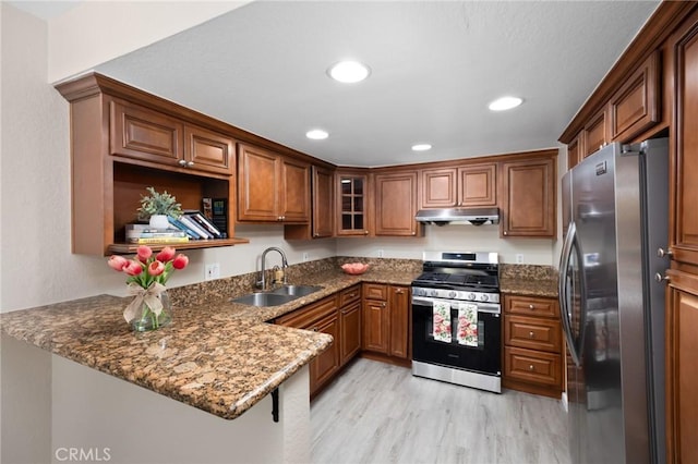 1304 Calle Grande Unit 68, Fullerton, CA 92835 - kitchen with appliances with stainless steel finishes, under cabinet range hood, a peninsula, light wood-type flooring, and dark stone counters