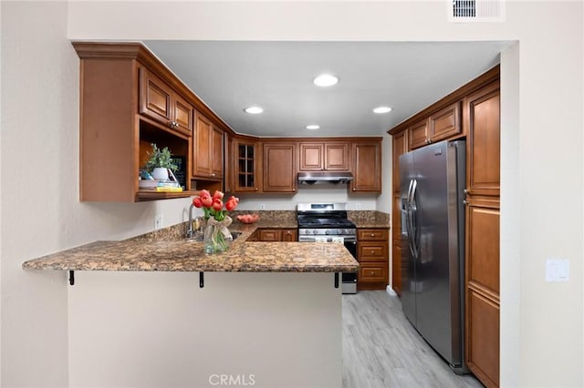1304 Calle Grande Unit 68, Fullerton, CA 92835 - kitchen with appliances with stainless steel finishes, under cabinet range hood, a peninsula, light wood finished floors, and a breakfast bar area