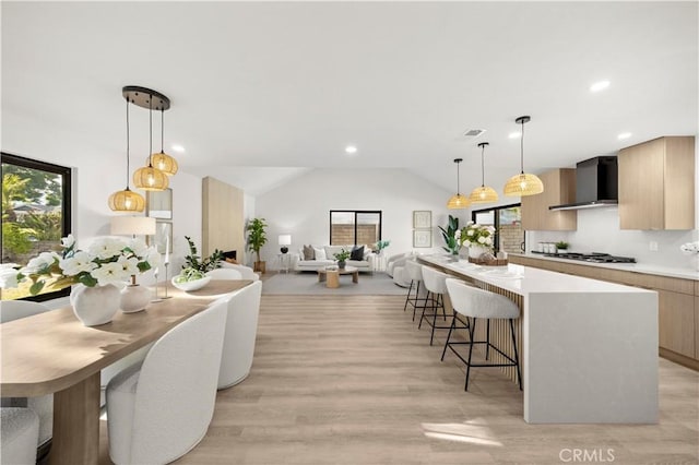 4700 Emerald Ave, La Verne, CA 91750 - kitchen with wall chimney range hood, modern cabinets, vaulted ceiling, light wood finished floors, and light countertops