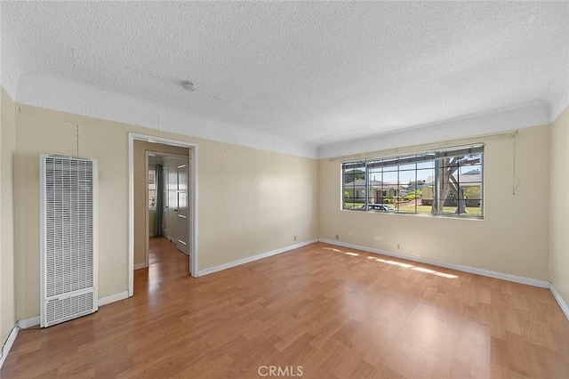 17229 Ardath Ave, Torrance, CA 90504 - spare room featuring a heating unit, light wood-style floors, a textured ceiling, and a smoke detector