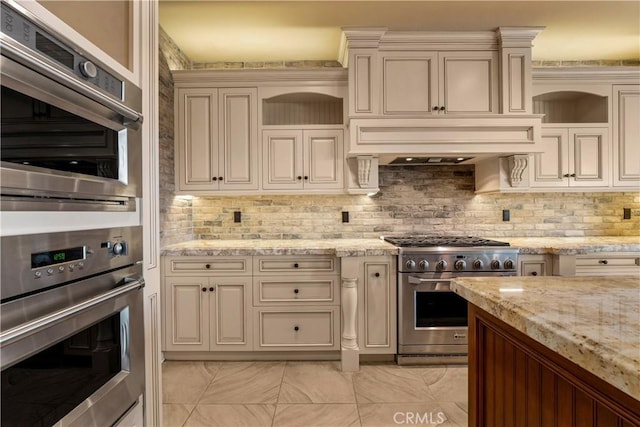 44277 Reidel St, Temecula, CA 92592 - kitchen featuring appliances with stainless steel finishes, cream cabinets, backsplash, light stone counters, and premium range hood