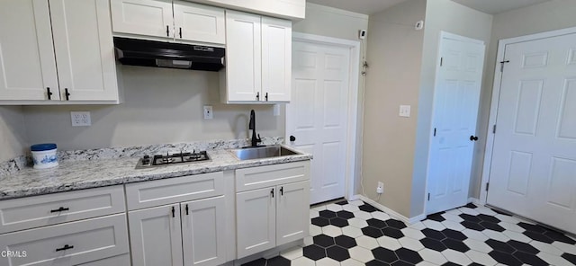 4141 Willow Trl, Frazier Park, CA 93225 - kitchen with under cabinet range hood, stainless steel gas stovetop, dark flooring, white cabinets, and light stone countertops