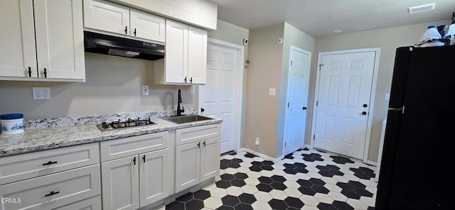 4141 Willow Trl, Frazier Park, CA 93225 - kitchen featuring under cabinet range hood, freestanding refrigerator, tile patterned floors, white cabinetry, and stainless steel gas cooktop