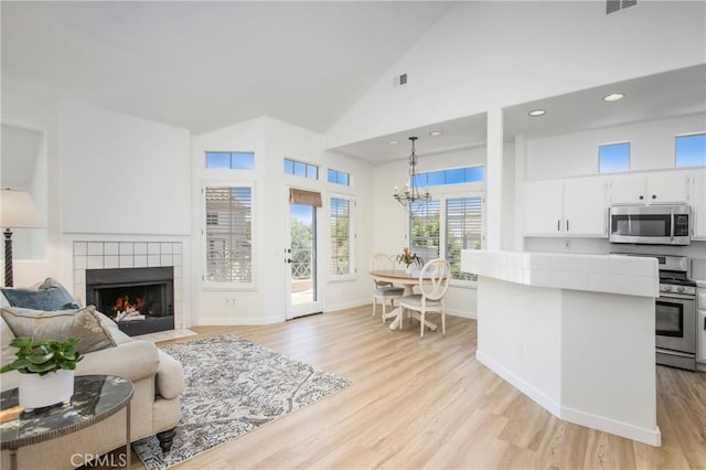 75 Shorebreaker Dr, Laguna Niguel, CA 92677 - living area featuring high vaulted ceiling, light wood finished floors, a fireplace, a chandelier, and recessed lighting