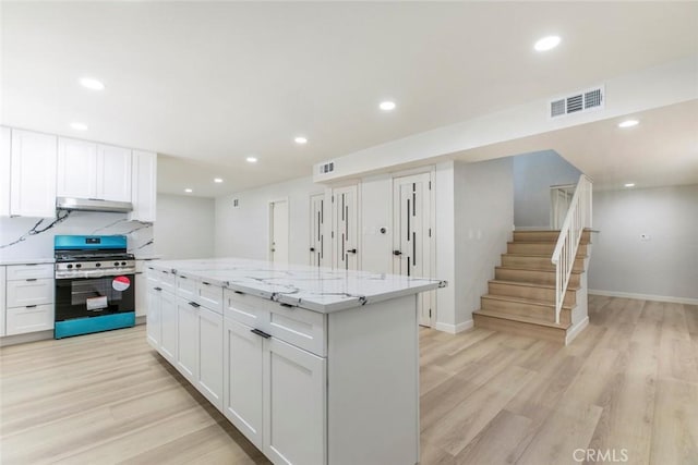 13119 Constable Ave, Granada Hills, CA 91344 - kitchen with stainless steel gas range, under cabinet range hood, light wood-style flooring, white cabinetry, and recessed lighting