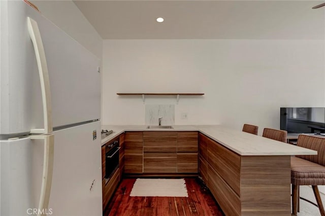 571 W 17th St, San Pedro, CA 90731 - kitchen featuring freestanding refrigerator, modern cabinets, a peninsula, brown cabinetry, and a kitchen bar