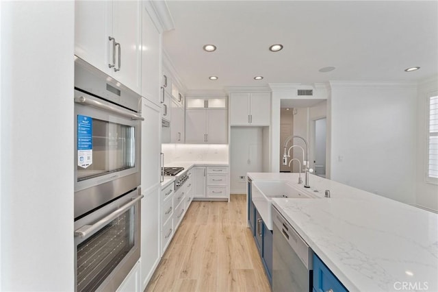 49 Eaglecreek, Irvine, CA 92618 - kitchen with stainless steel appliances, ornamental molding, white cabinets, light wood finished floors, and recessed lighting