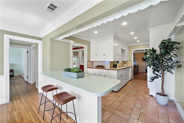 9662 Crosby Ave, Garden Grove, CA 92844 - kitchen with white cabinets, light countertops, a kitchen bar, ornamental molding, and recessed lighting