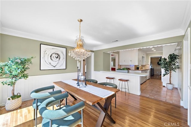 9662 Crosby Ave, Garden Grove, CA 92844 - dining space with a chandelier, crown molding, wainscoting, and light wood-type flooring