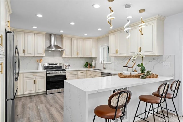 4802 Brookway Ave, Yorba Linda, CA 92886 - kitchen featuring appliances with stainless steel finishes, wall chimney exhaust hood, a peninsula, light wood-style flooring, and a kitchen bar