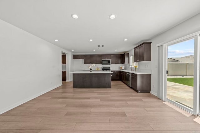28339 Levi Way, Menifee, CA 92585 - kitchen with appliances with stainless steel finishes, light wood finished floors, recessed lighting, dark brown cabinetry, and a center island