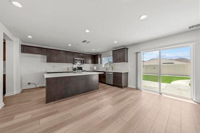 28339 Levi Way, Menifee, CA 92585 - kitchen with stainless steel appliances, dark brown cabinets, light countertops, light wood-style flooring, and healthy amount of natural light