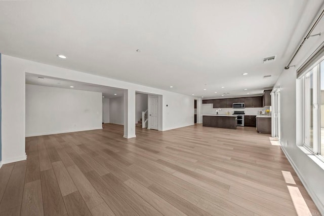 28339 Levi Way, Menifee, CA 92585 - unfurnished living room featuring light wood-style flooring, recessed lighting, healthy amount of natural light, and stairway