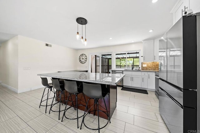 7971 Jade Coast Rd, San Diego, CA 92126 - kitchen with appliances with stainless steel finishes, a kitchen island, white cabinetry, a kitchen breakfast bar, and light stone countertops