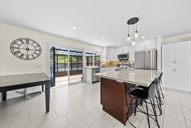 7971 Jade Coast Rd, San Diego, CA 92126 - kitchen with stainless steel appliances, decorative backsplash, a kitchen breakfast bar, a center island, and decorative light fixtures