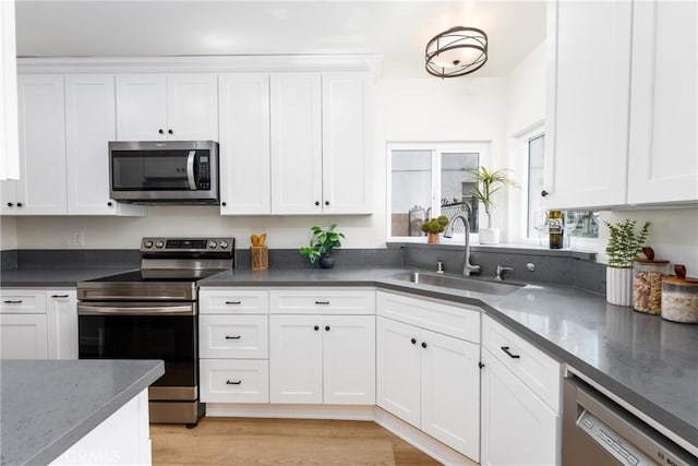 2283 Gaviota Ave, Signal Hill, CA 90755 - kitchen with appliances with stainless steel finishes, white cabinets, dark stone countertops, and light wood-style flooring