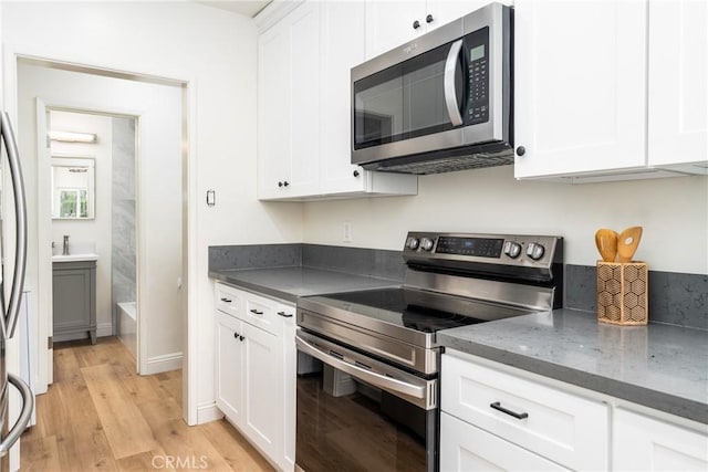 2283 Gaviota Ave, Signal Hill, CA 90755 - kitchen with stainless steel appliances, white cabinets, light wood-style flooring, and dark stone countertops