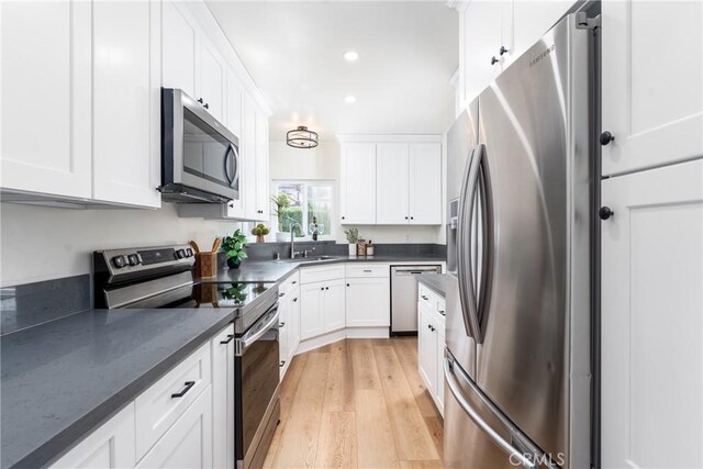 2283 Gaviota Ave, Signal Hill, CA 90755 - kitchen with stainless steel appliances, light wood-style floors, white cabinetry, recessed lighting, and dark stone countertops