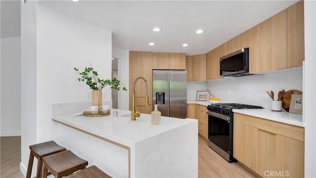 19081 Wildwood Cir, Lake Forest, CA 92679 - kitchen featuring appliances with stainless steel finishes, modern cabinets, a breakfast bar, a peninsula, and light wood-style floors