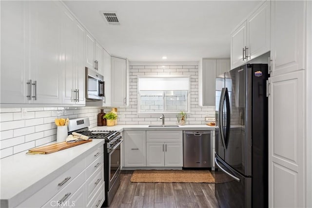11243 Gaviota Ave, Granada Hills, CA 91344 - kitchen with appliances with stainless steel finishes, dark wood-type flooring, tasteful backsplash, light countertops, and white cabinetry