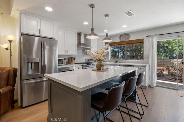2151 Stonefield Pl, Riverside, CA 92506 - kitchen with stainless steel appliances, wall chimney range hood, light wood finished floors, white cabinetry, and a kitchen island
