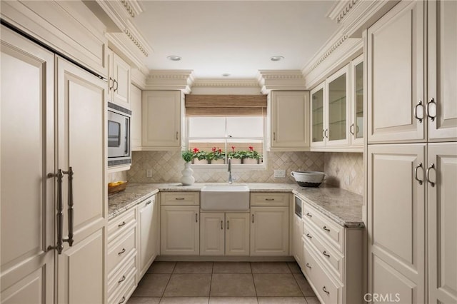 816 Via Lido Nord, Newport Beach, CA 92663 - kitchen featuring light tile patterned floors, tasteful backsplash, stainless steel microwave, glass insert cabinets, and light stone countertops