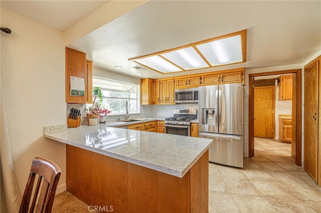 14320 Kiptree Dr, Lake Hughes, CA 93532 - kitchen featuring appliances with stainless steel finishes, a peninsula, brown cabinetry, light stone counters, and decorative backsplash